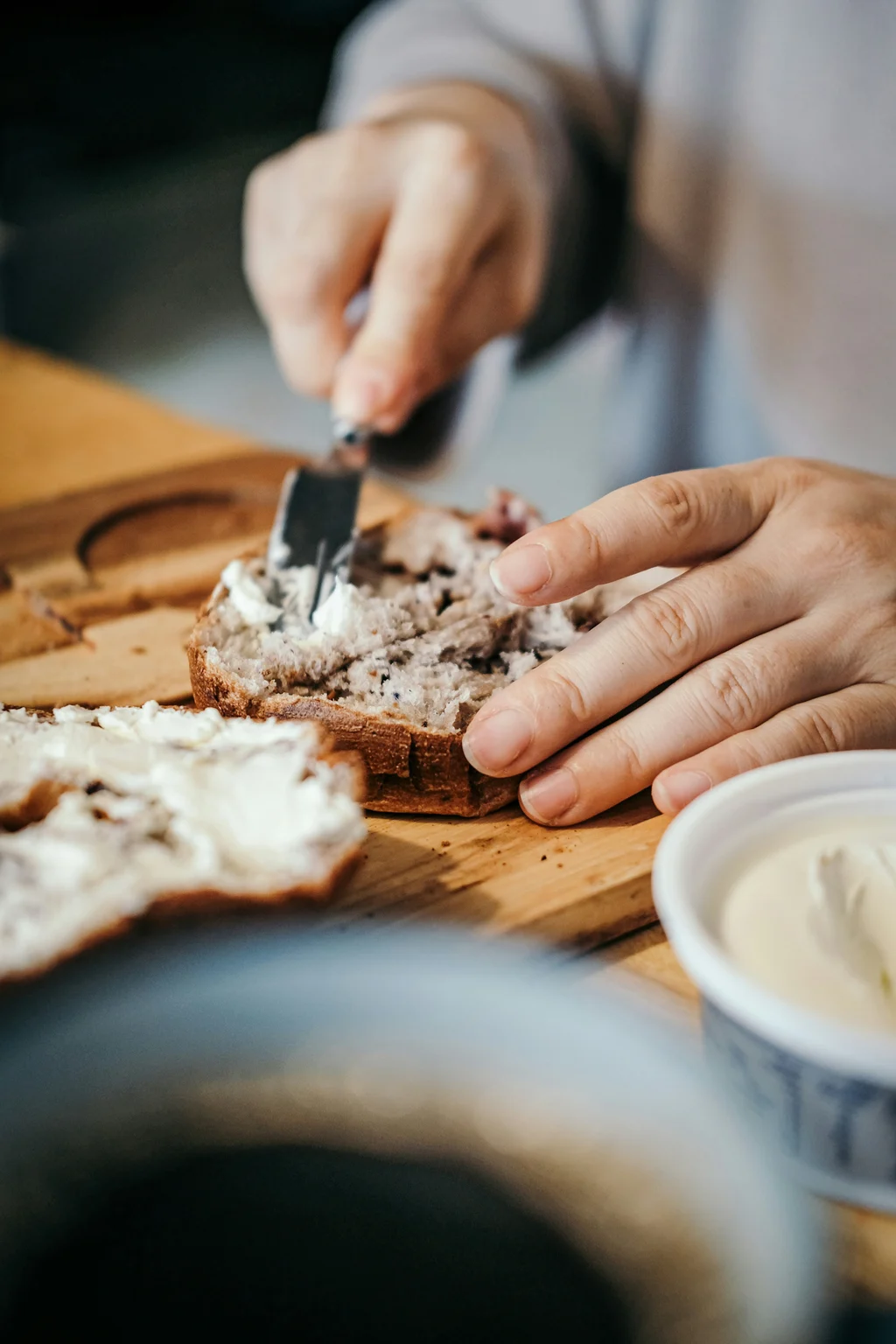 Person spreading cream cheese on bread, illustrating the best cream cheese for baking and everyday kitchen use